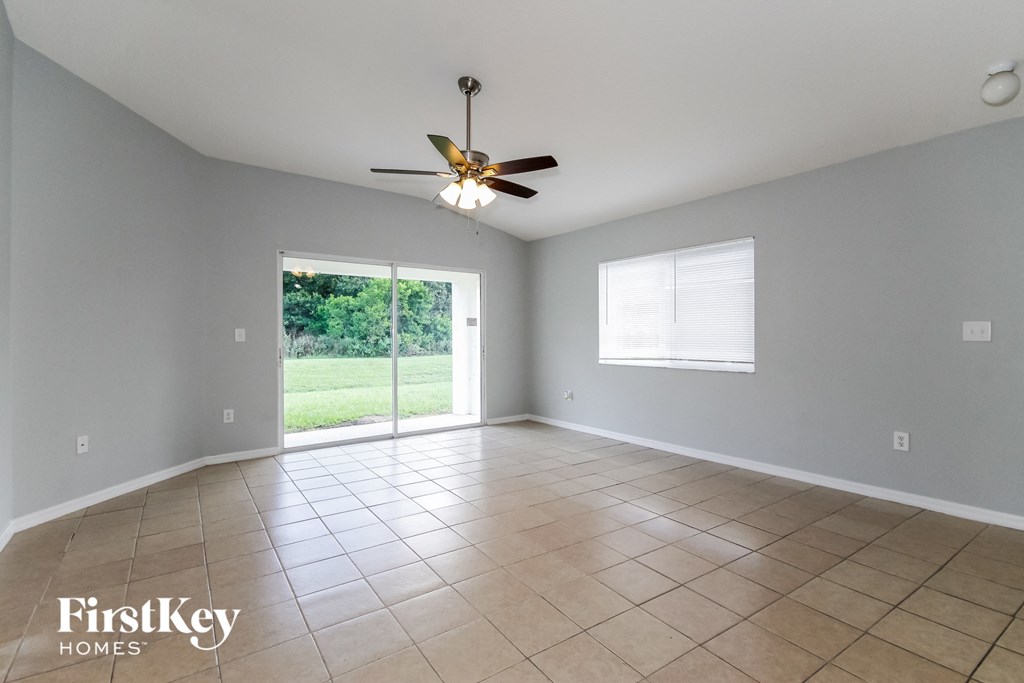 an empty living room with a ceiling fan and tiled floors