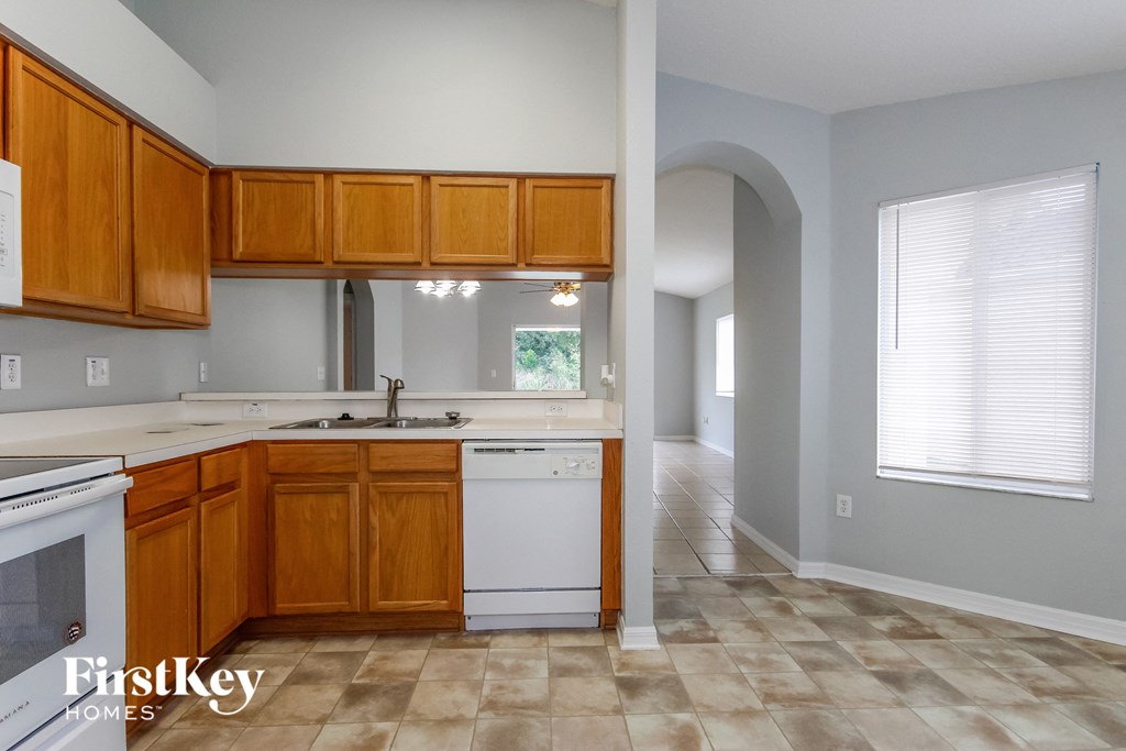 an empty kitchen with wooden cabinets and white appliances
