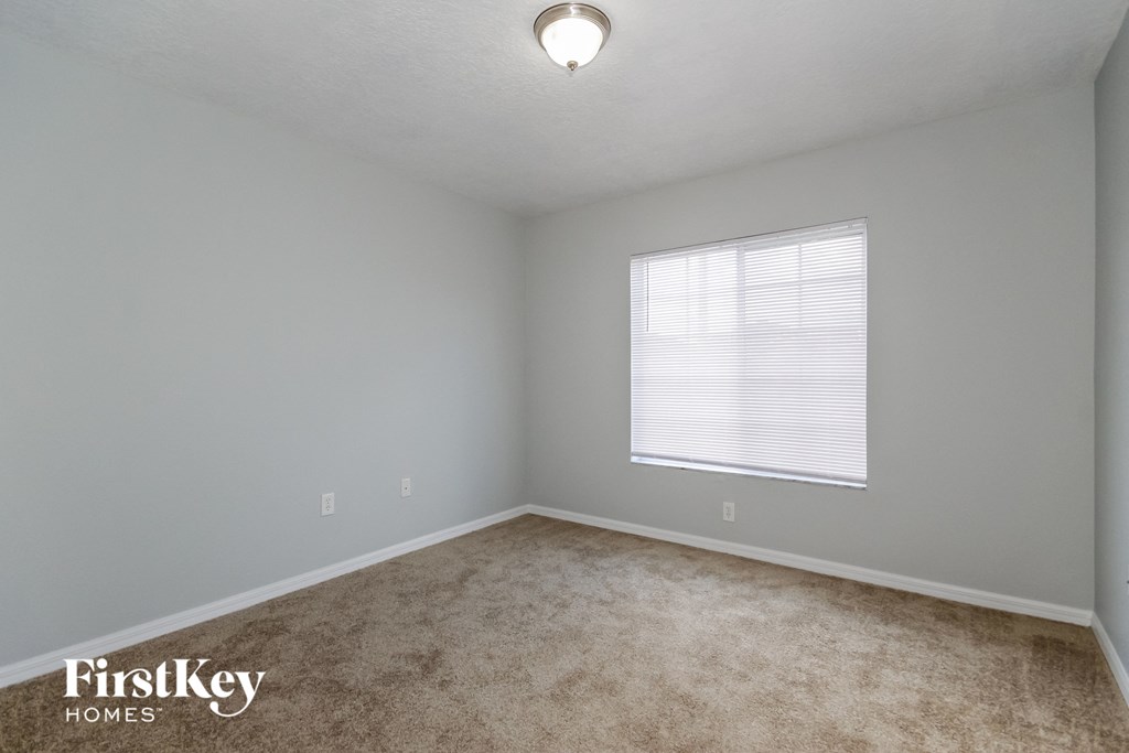 the spacious bedroom with carpeted flooring and a large window