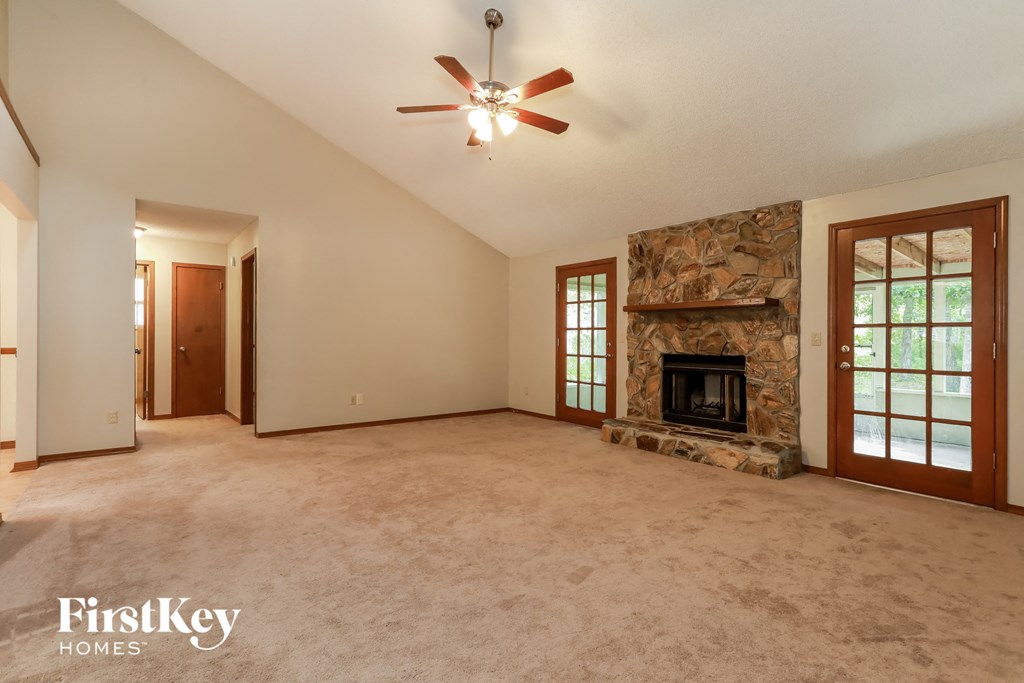 A spacious room with a stone fireplace and a ceiling fan.