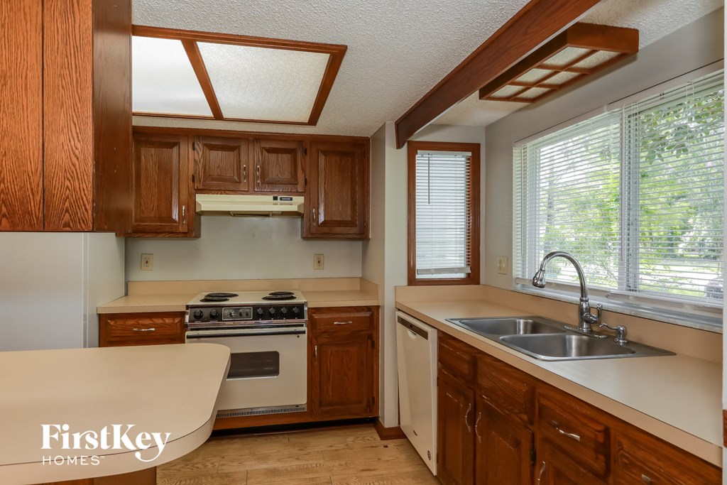 A kitchen with wooden cabinets and a stove top oven.