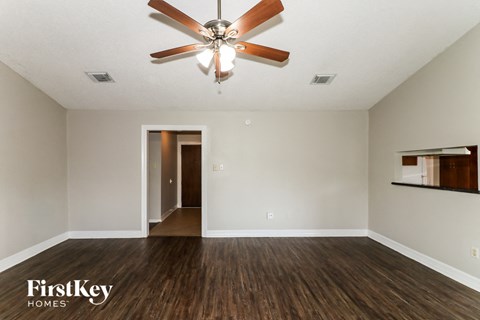 A room with a ceiling fan and wooden floors.