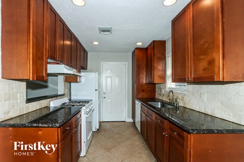 A kitchen with brown cabinets and a black counter top.