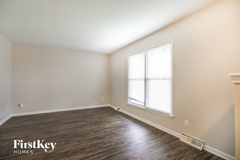 the living room of a home with wood flooring and a large window