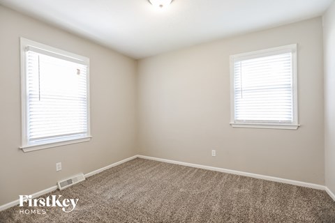 a bedroom with two windows and a carpeted floor