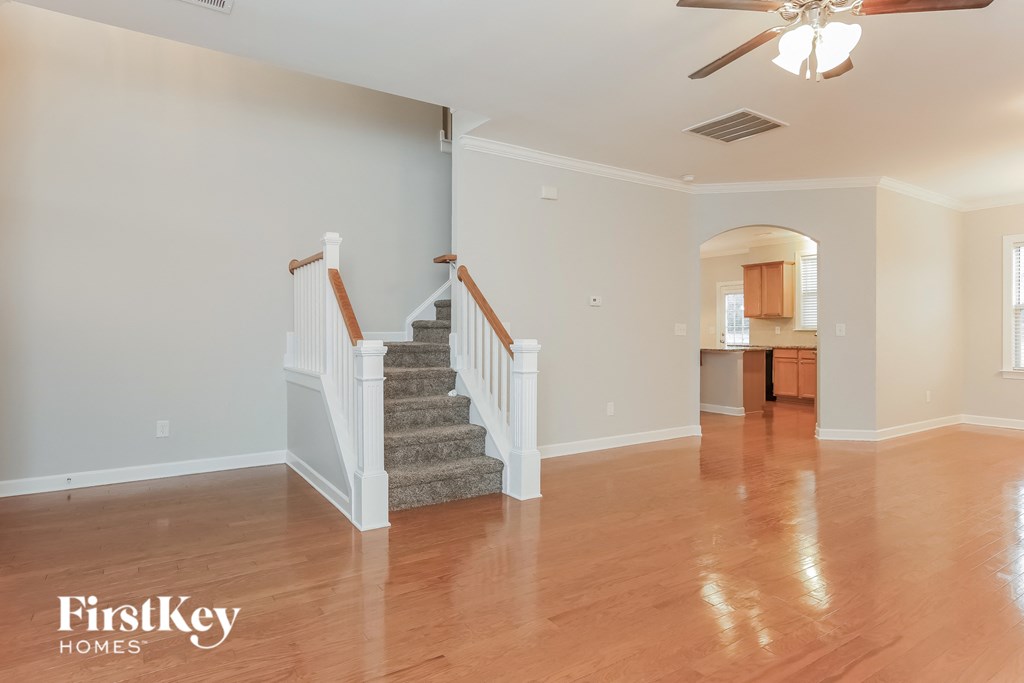 A spacious room with a staircase and a ceiling fan.
