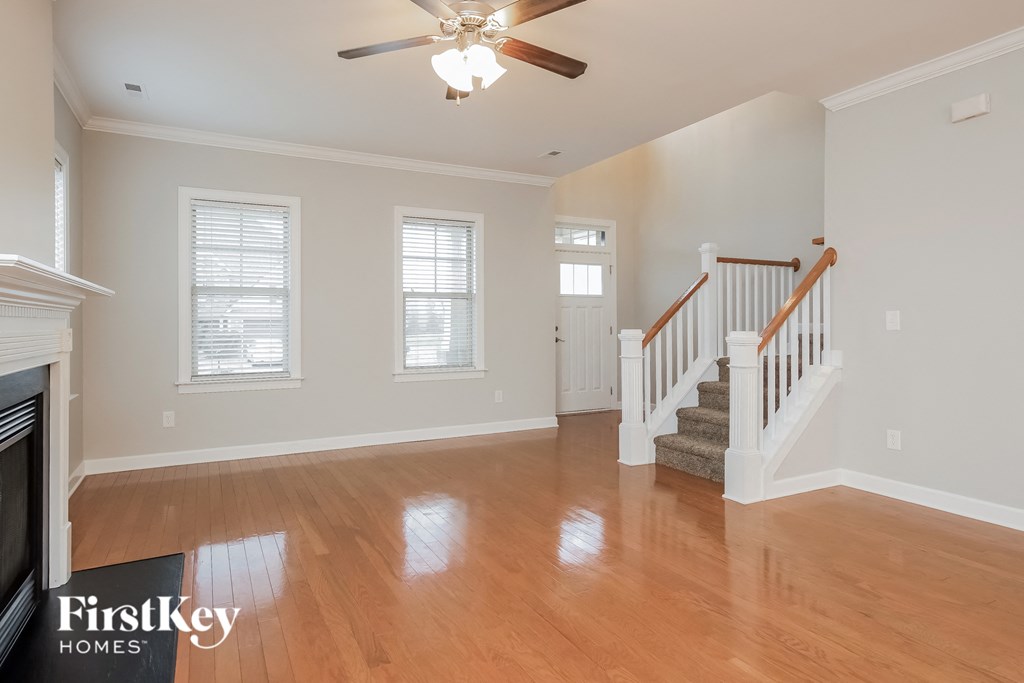 A spacious living room with a fireplace and a staircase.