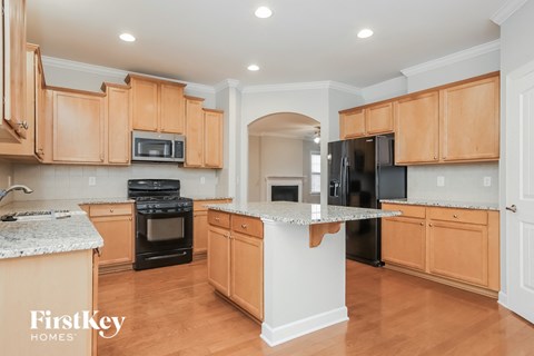 A kitchen with wooden cabinets and a marble island.