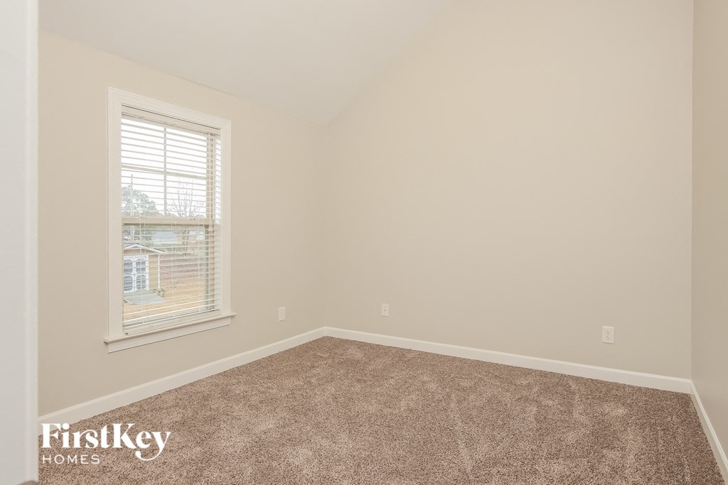 A room with a carpeted floor and a window showing a building outside.