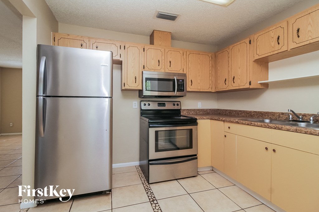 A kitchen with a stainless steel refrigerator and a black stove top oven.