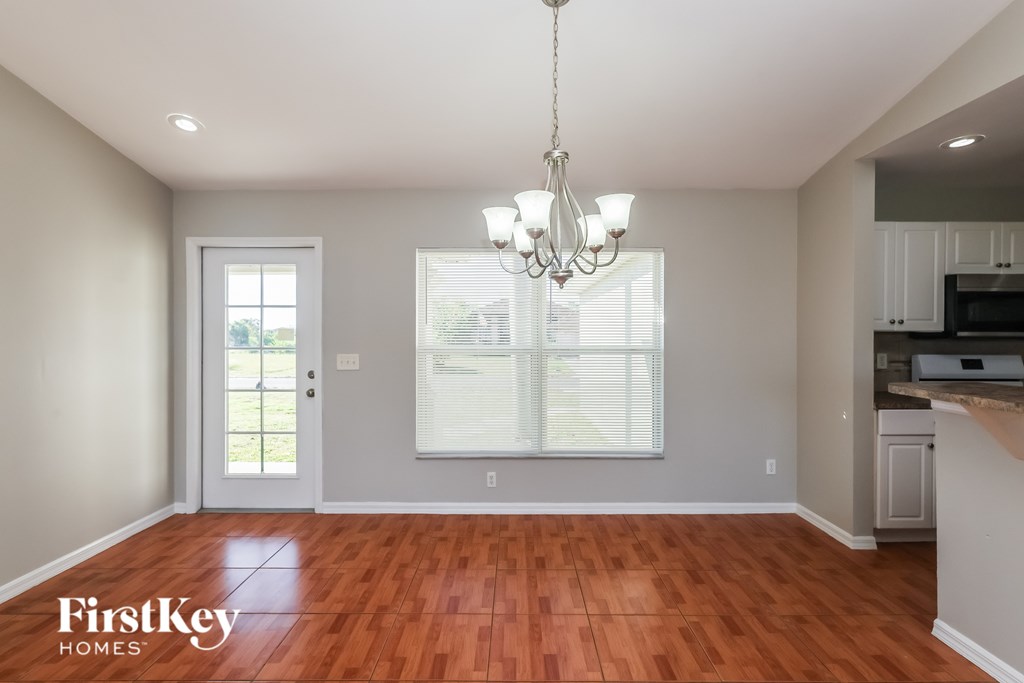 A well-lit room with a wooden floor and a chandelier hanging from the ceiling.