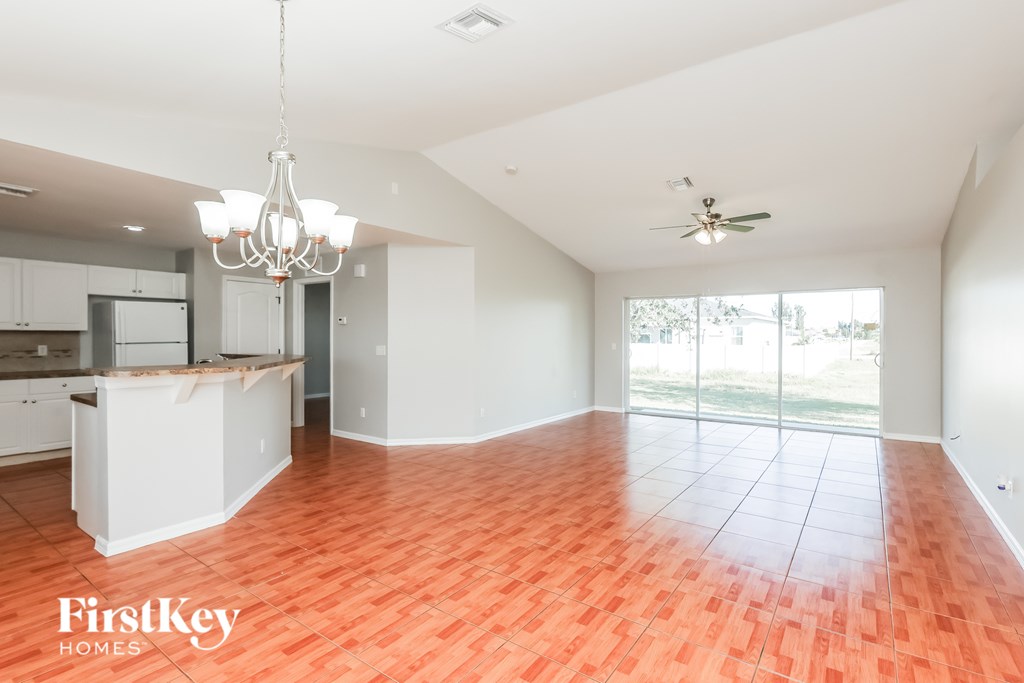 A spacious living room with a kitchen area in the background.