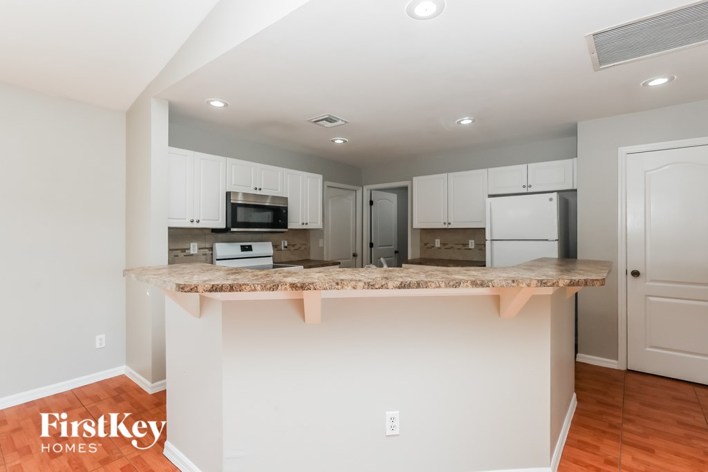 A kitchen with a countertop and cabinets is shown in an empty room.