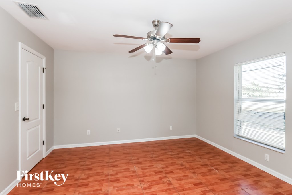 A room with a ceiling fan and a window with blinds.