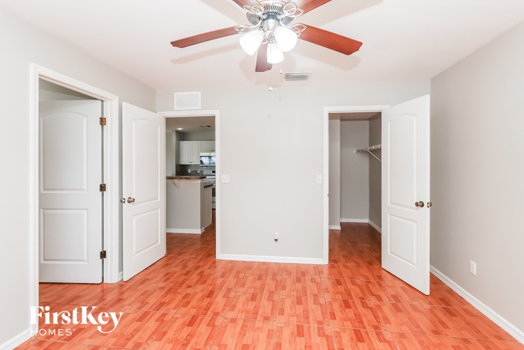 A room with a ceiling fan and wooden floors.