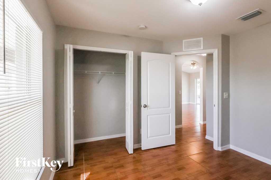 A room with a wooden floor and white walls, with a glass door leading to another room.