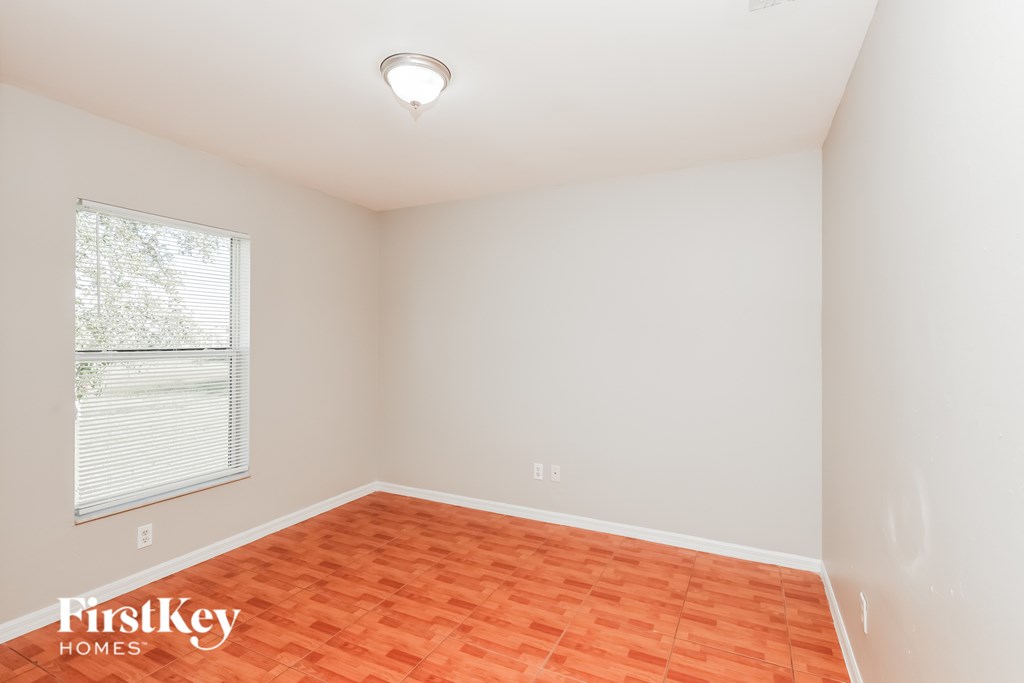 A room with a window and a wooden floor.