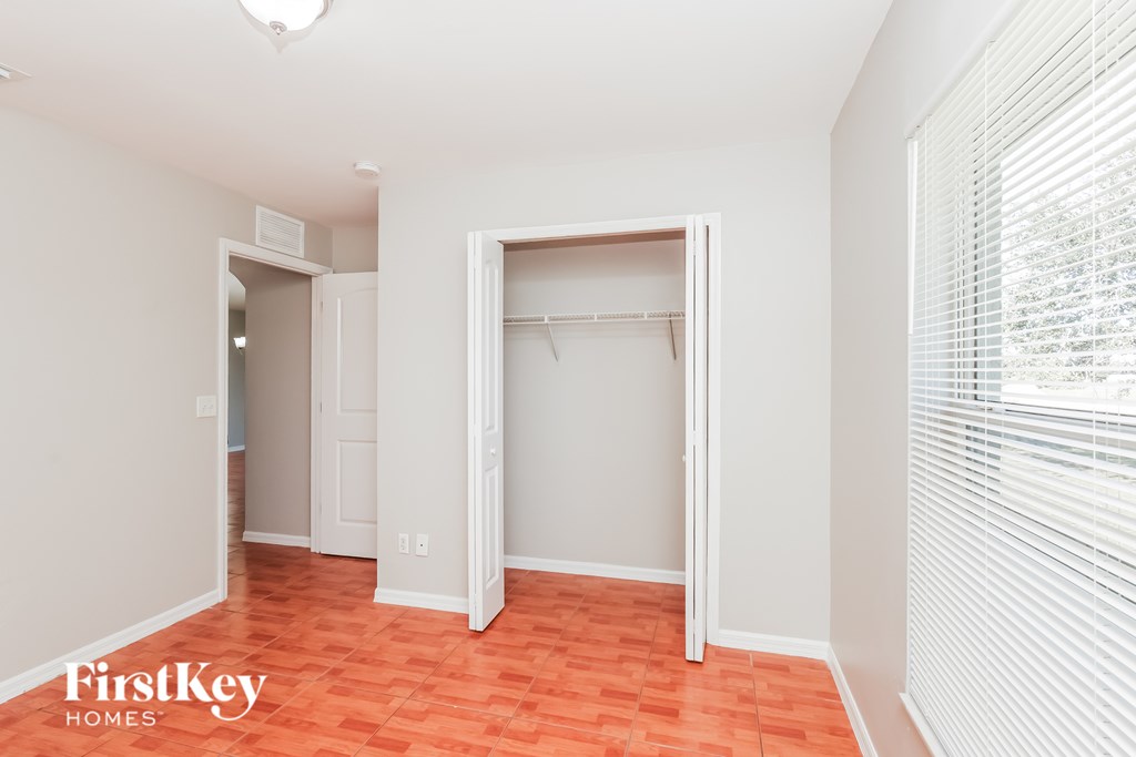 A room with a red floor and a white wall with a closet.