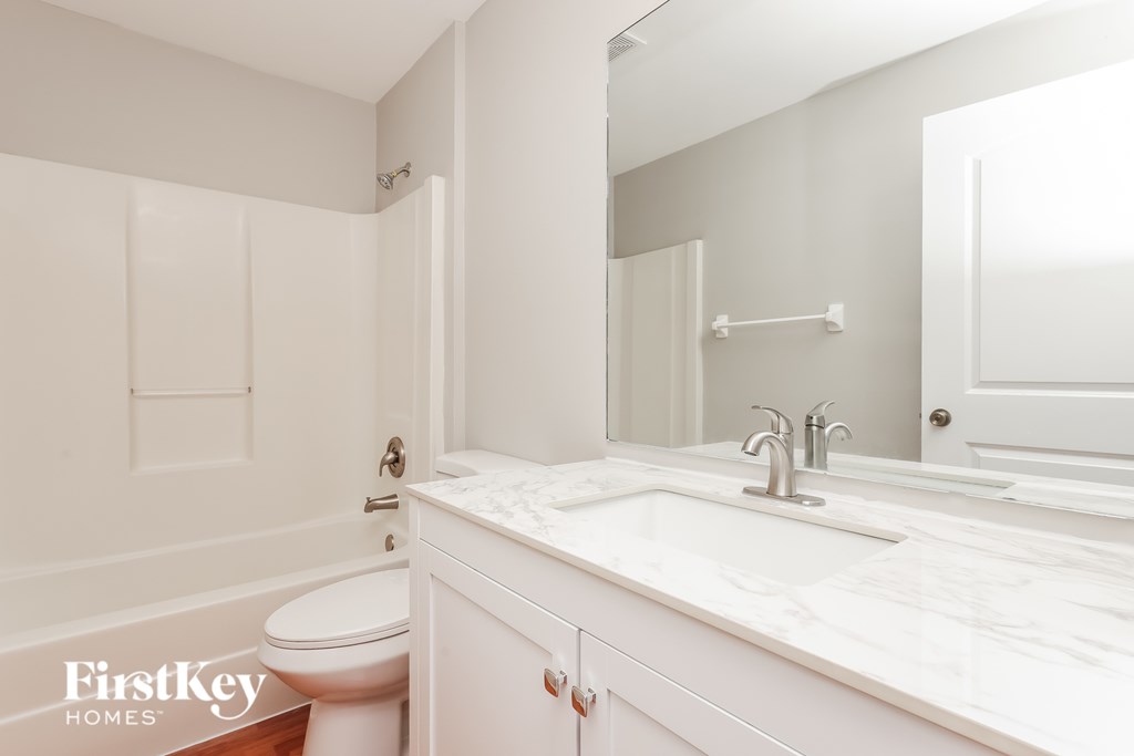 A white bathroom with a toilet, sink, and mirror.