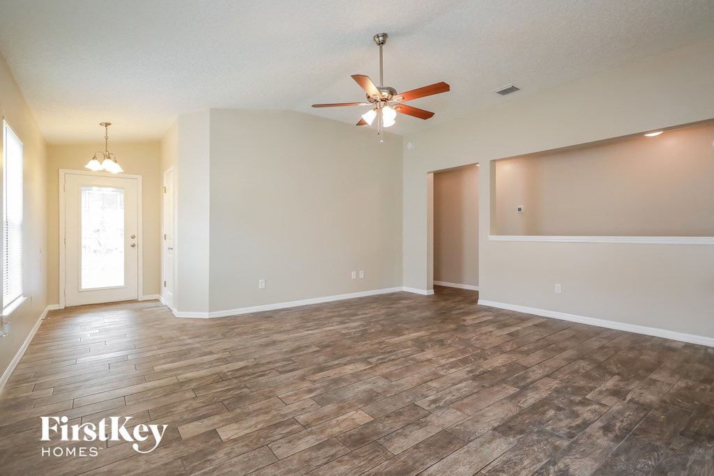 A spacious room with wooden flooring and a ceiling fan.
