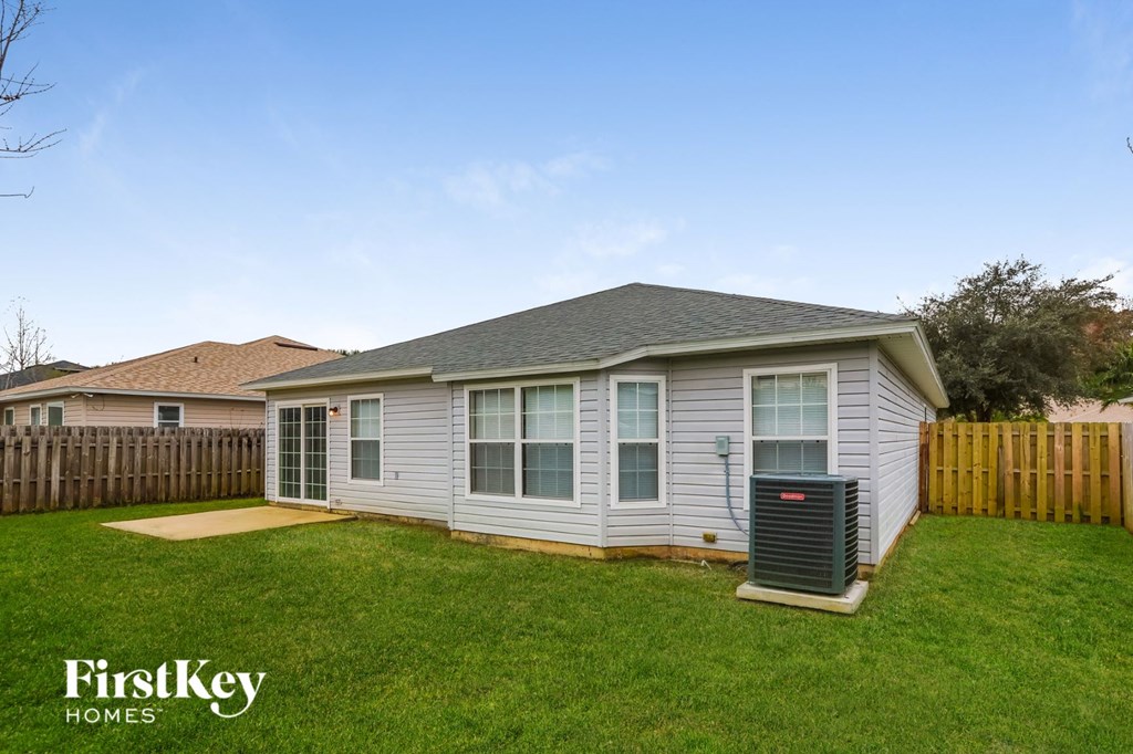 A small house with a brown roof and a grey siding is shown with a grassy lawn in front.
