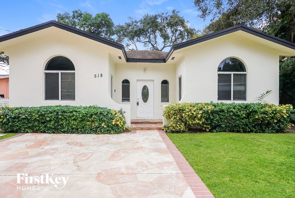 a white house with black shuttered windows and a lawn