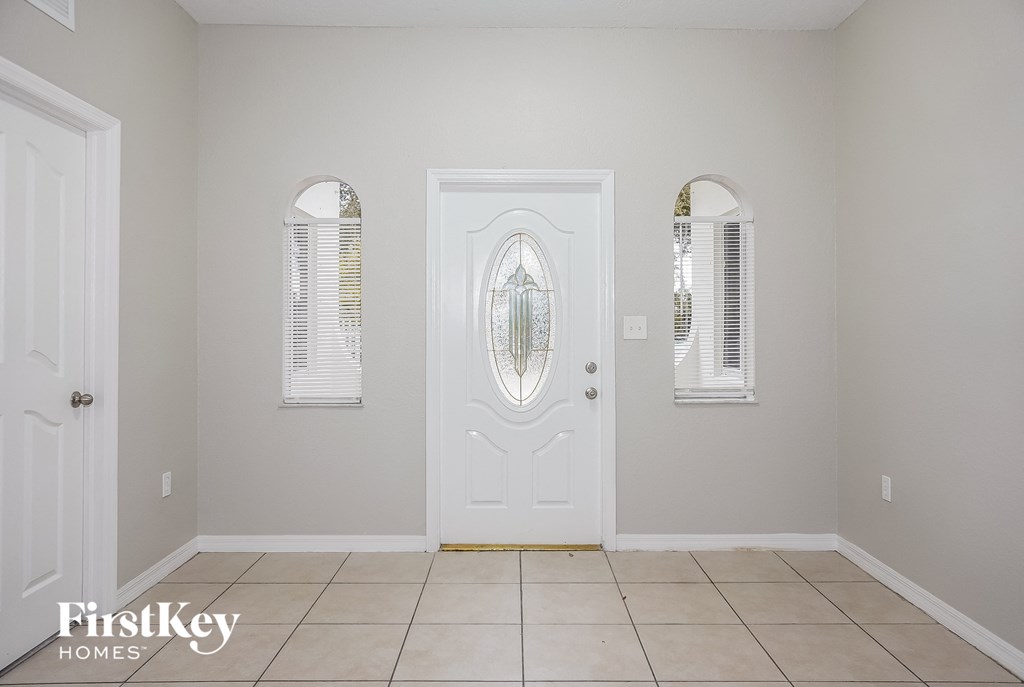 a room with a white door with three windows and a tiled floor