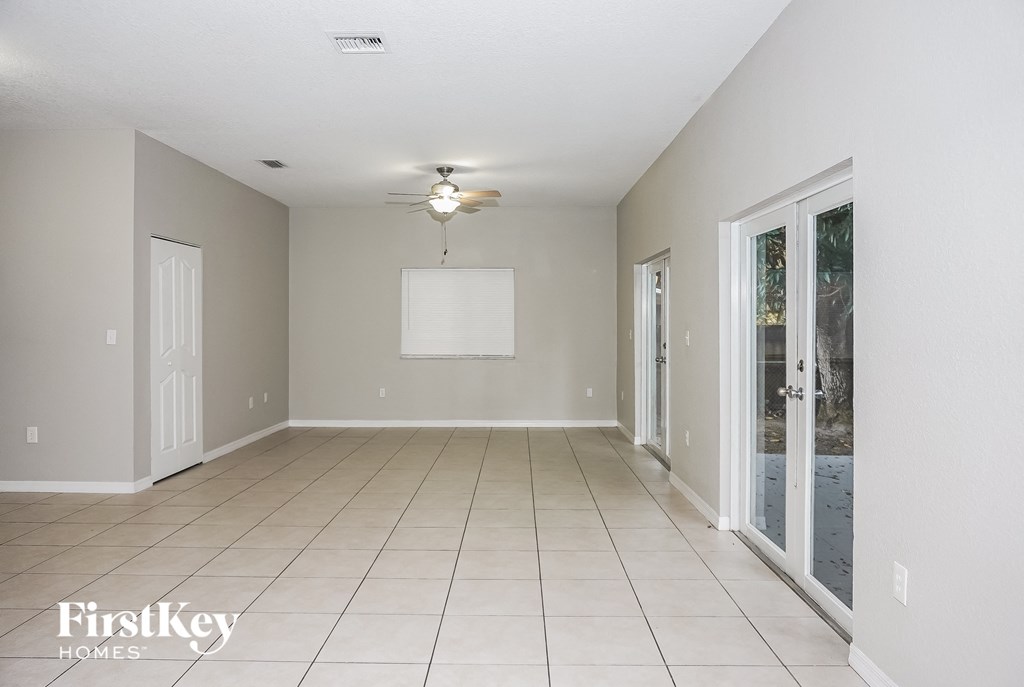 an empty living room with a ceiling fan and doors to a patio