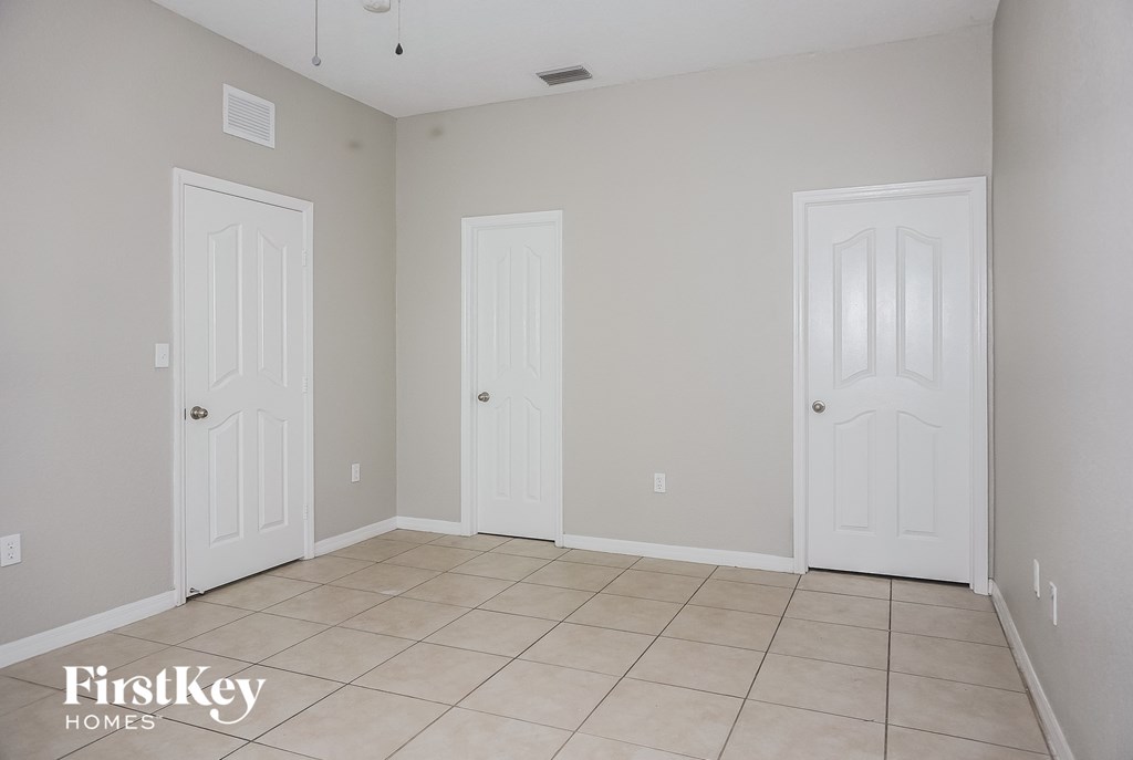 a empty room with two white doors and a tiled floor