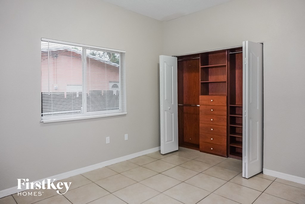 a closet with a window and a door to a room with a dresser