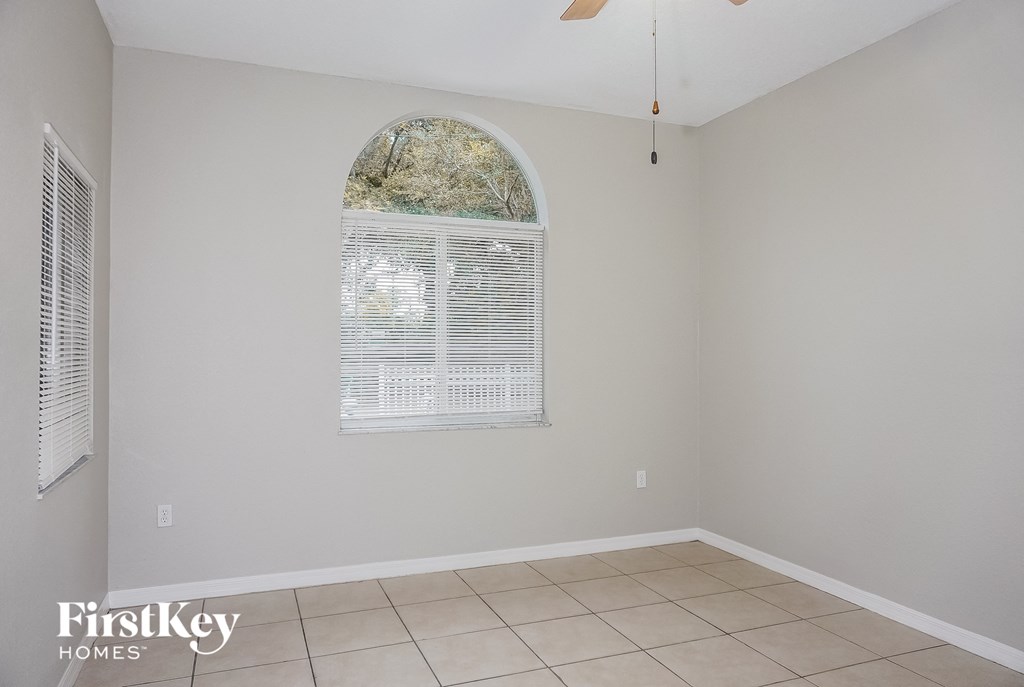 a living room with an arched window and a tiled floor