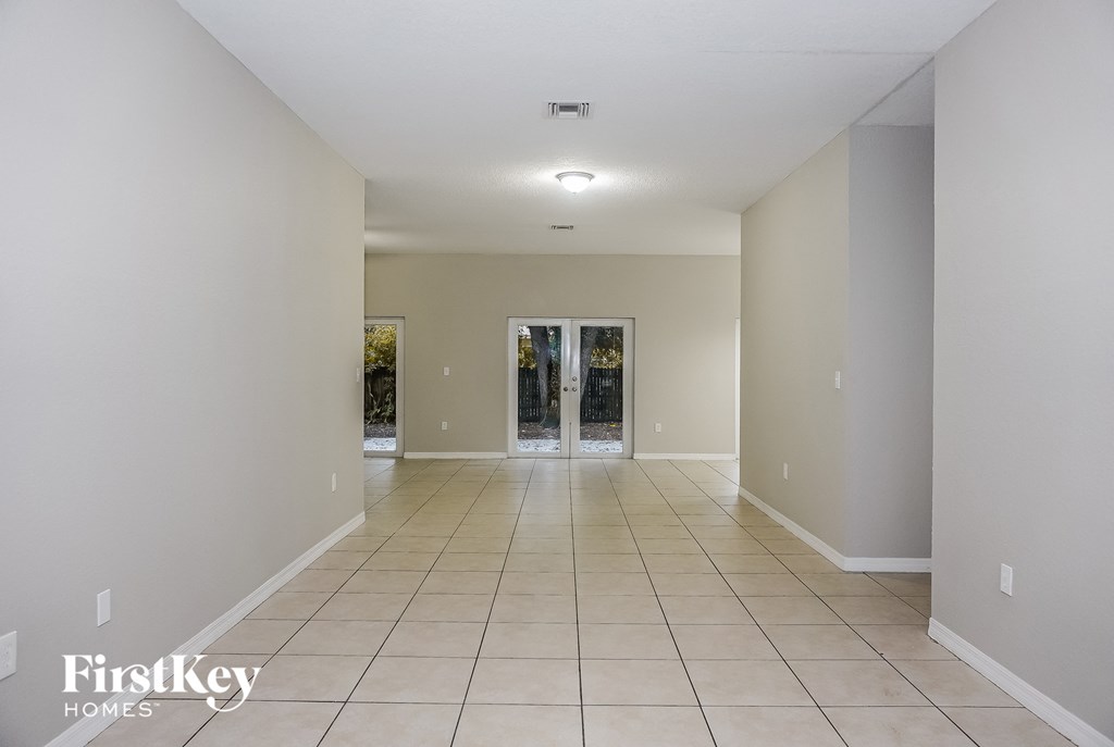 a spacious living room with a tiled floor and doors to the patio