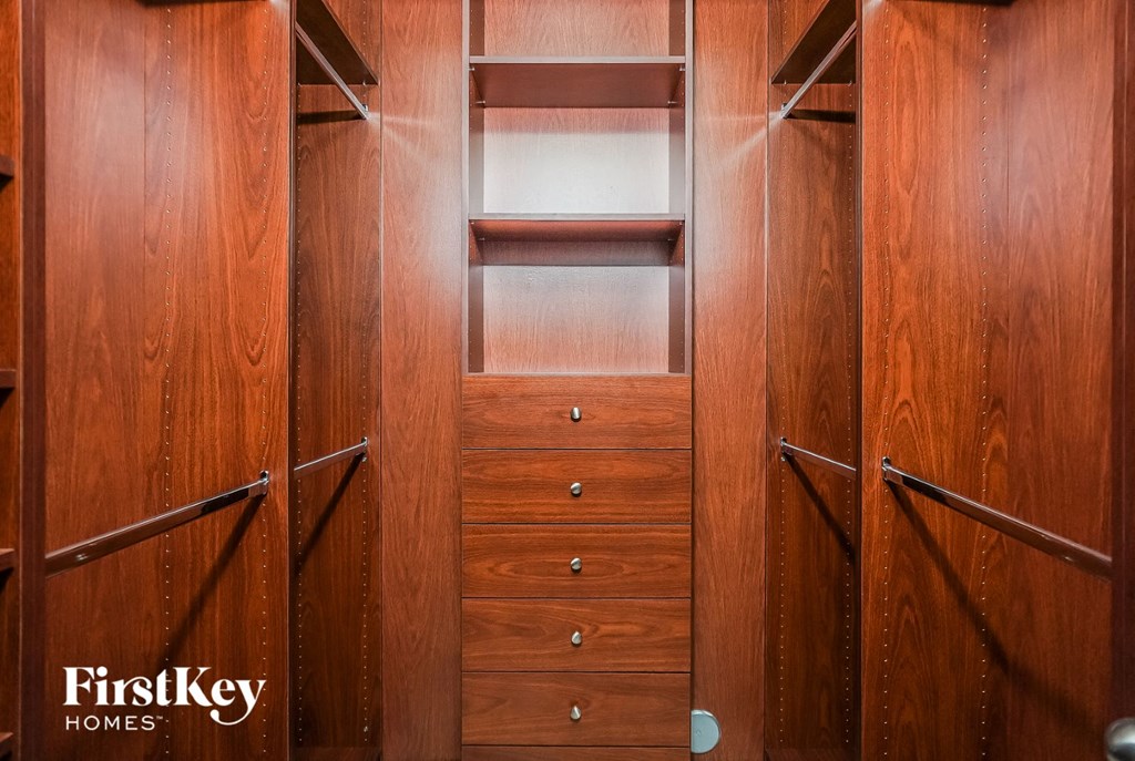 a walk in closet with wooden shelves and drawers