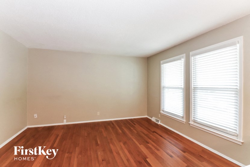 A room with wooden floors and two windows.