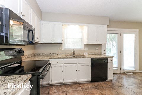 A kitchen with white cabinets and a black dishwasher.