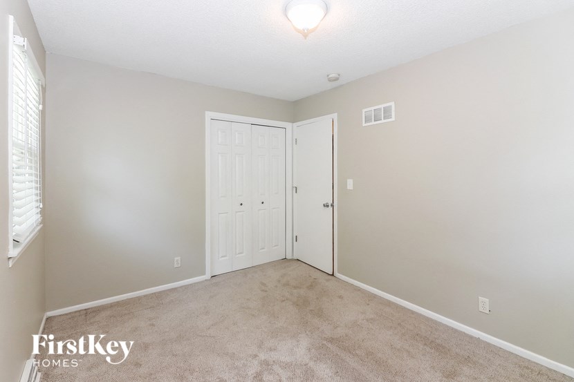 A bedroom with a carpeted floor and a white door.