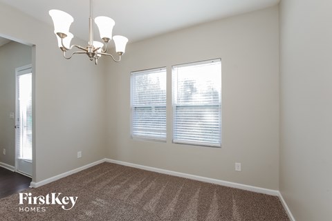 a living room with two windows and a rug and a chandelier