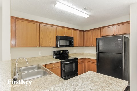 A kitchen with wooden cabinets and black appliances.
