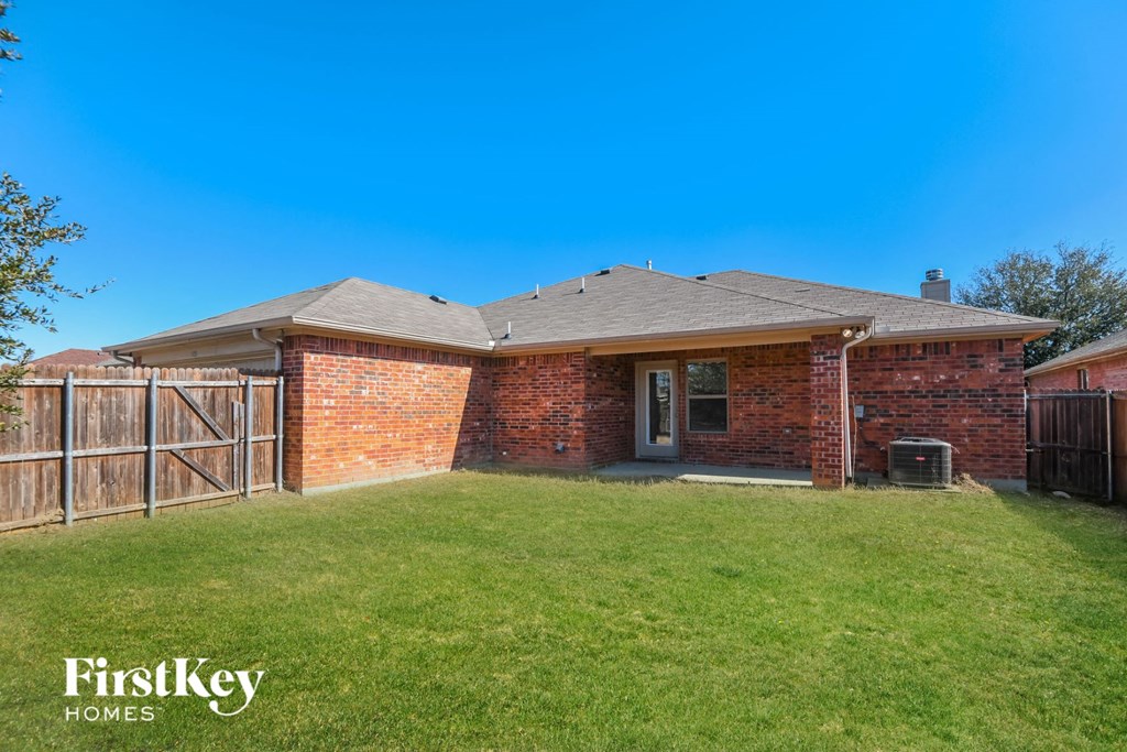 the backyard of a brick house with a yard and a fence