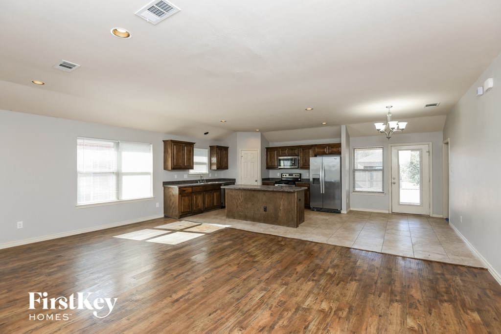 an open kitchen and living room with wood floors and white walls