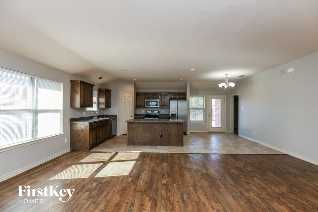 an open kitchen and living room with wood flooring and a large window
