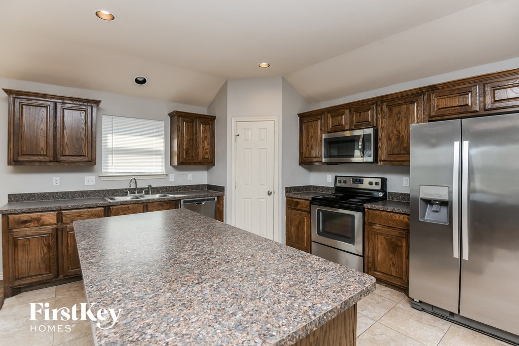 a kitchen with granite countertops and stainless steel appliances and wooden cabinets