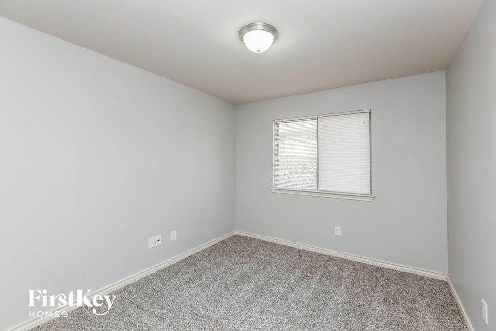 a bedroom with white walls and carpet and a window