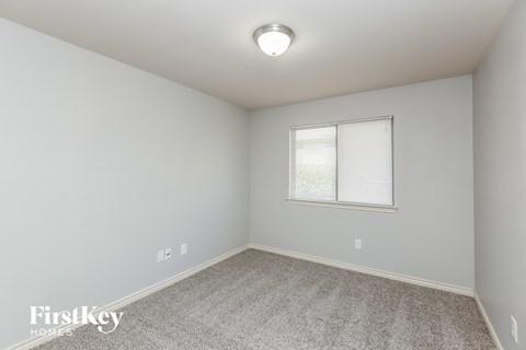 a bedroom with white walls and carpet and a window