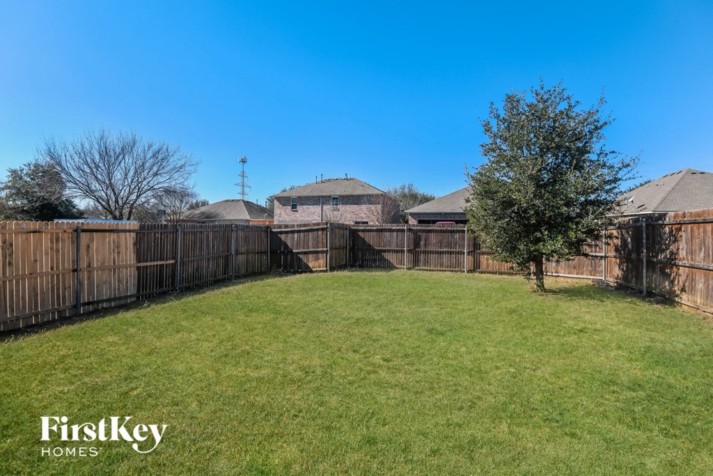 a backyard with a wooden fence and a green lawn