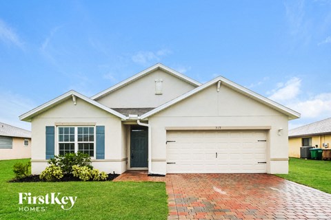 a white house with a garage door and grass