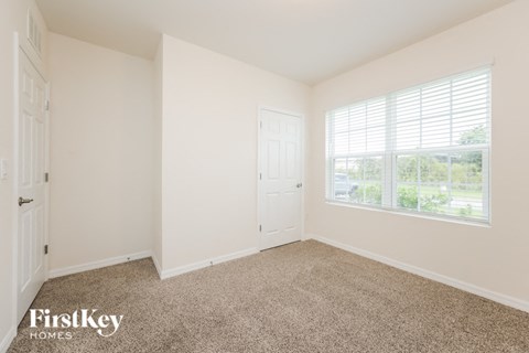 a bedroom with carpet and a door and window