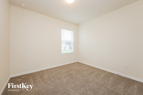 a spacious room with carpet and a window