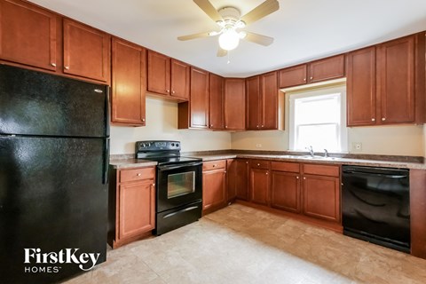 A kitchen with brown cabinets and black appliances.