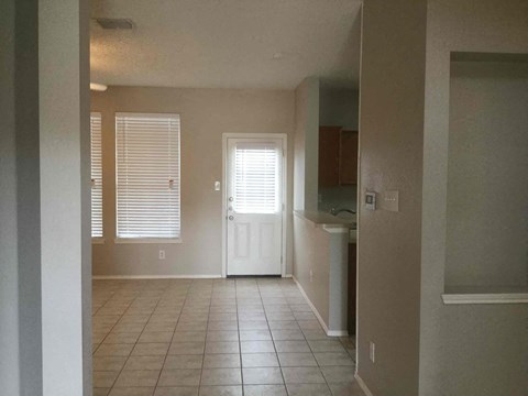 an empty living room with a tile floor and a white door
